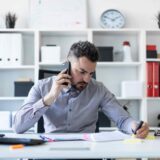 Man looking down at his notes, with phone in hand.