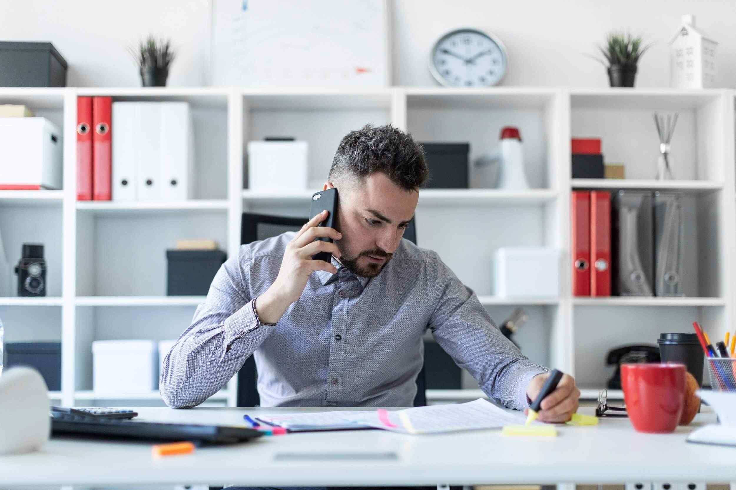 Man looking down at his notes, with phone in hand.